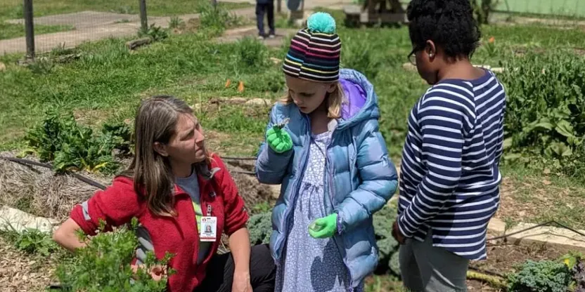 An adult and two children in a garden.