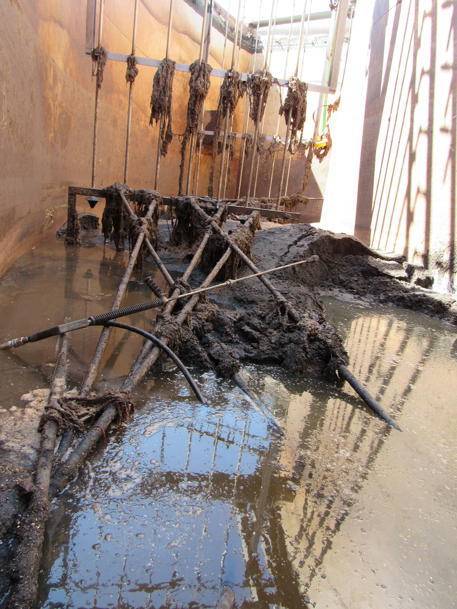 Large amount of accumulated grit, flushable wipes, and rags in a wastewater treatment basin. The grit is comprised of sand, gravel, plastic, and other inorganic material flushed into the wastewater system.