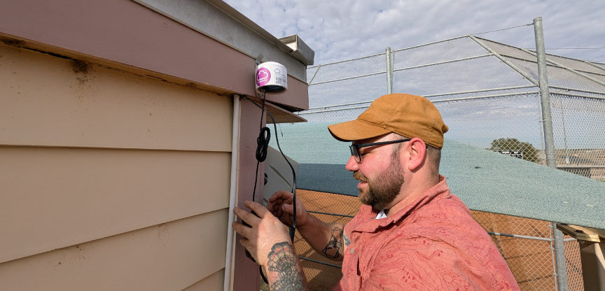 Brian Hess installs a Purple Air sensor at Noack Sports Complex.