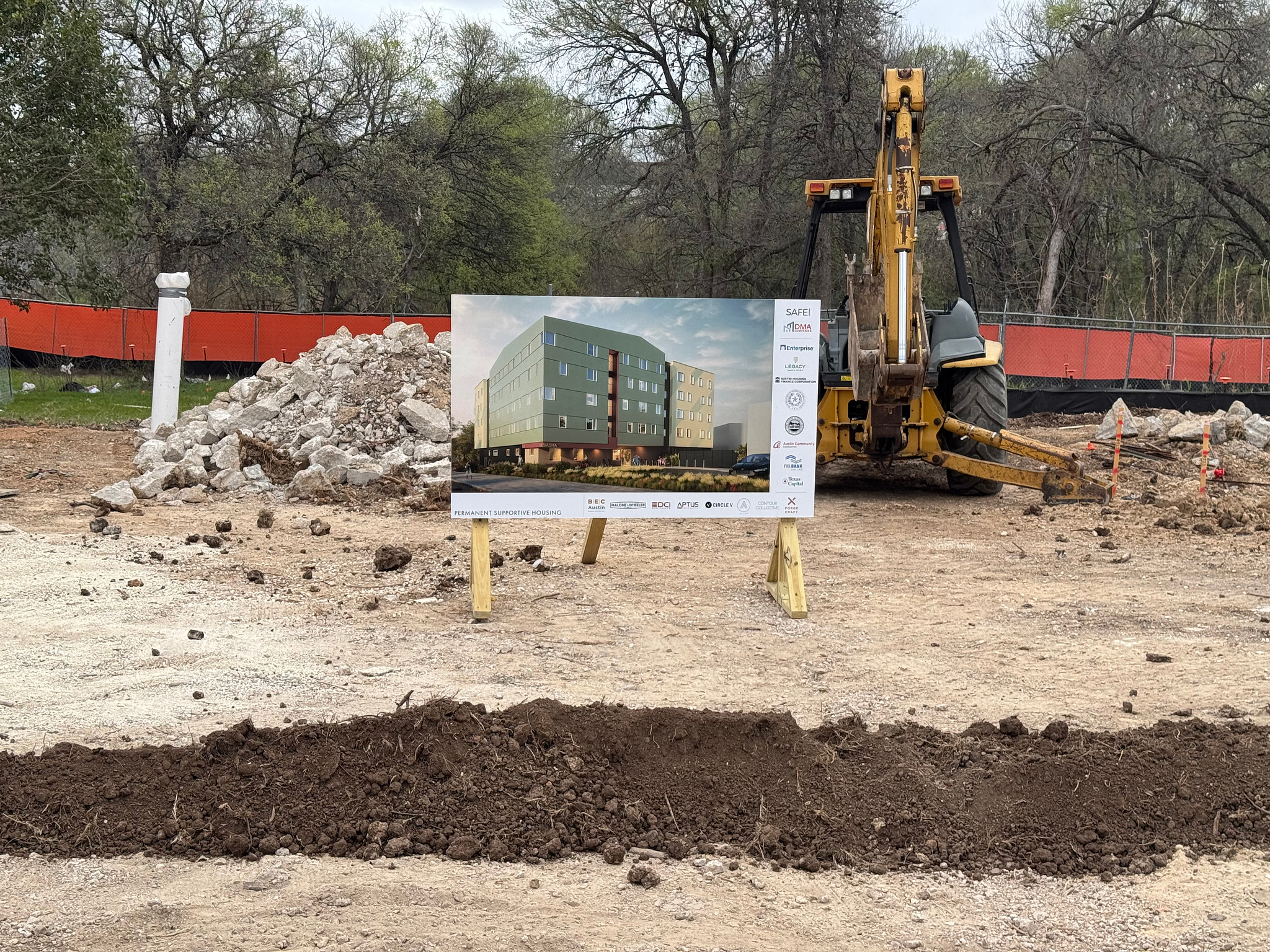 Image shows dirt and stone piled up, along with a digger machine. There is also a rendering depicting what The Sasha will look like once completed.