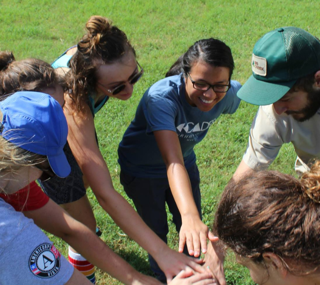AmeriCorps VISTA members participating in an outdoor hands-in huddle
