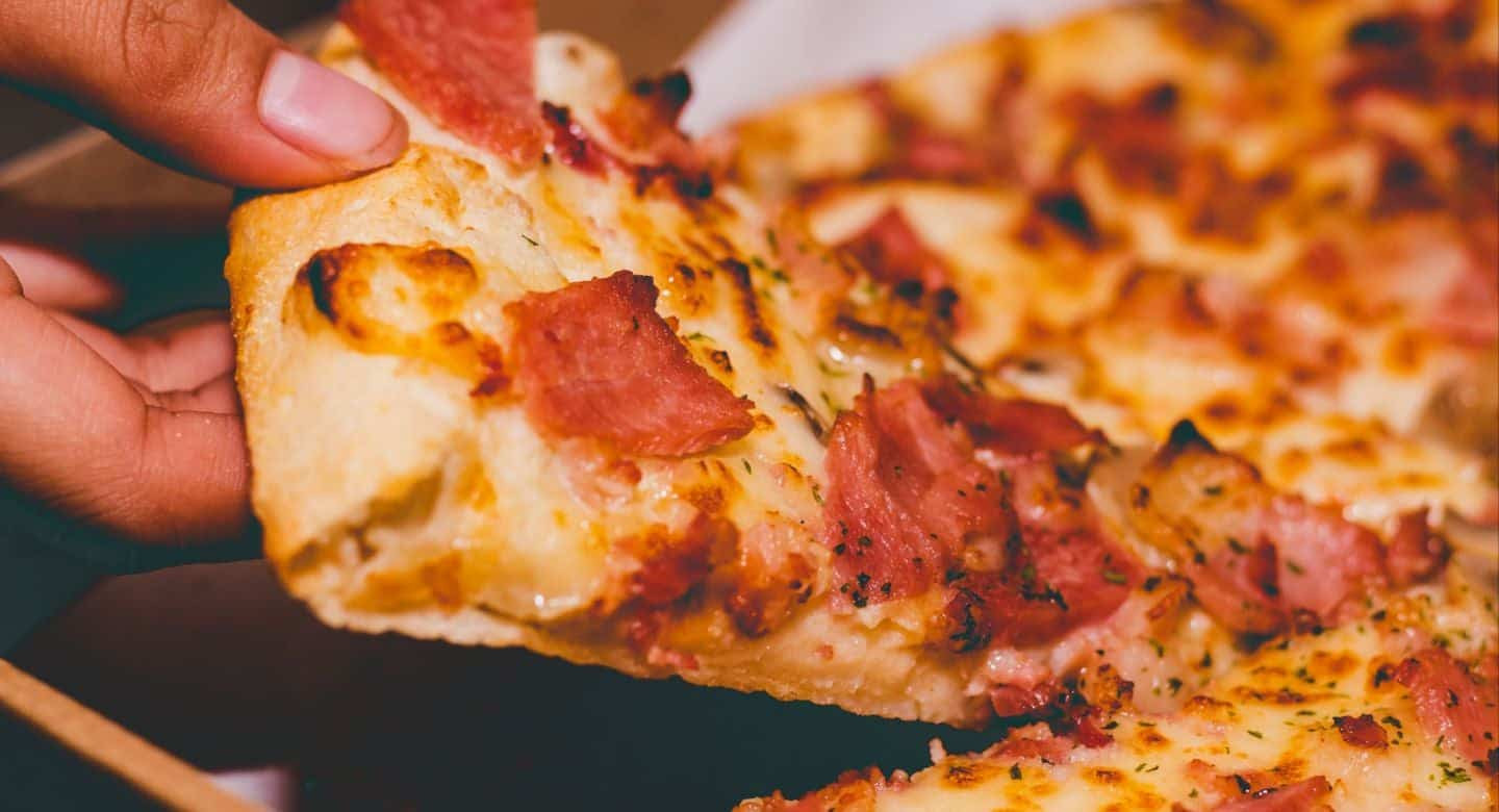 Closeup of hand grabbing a piece of pizza