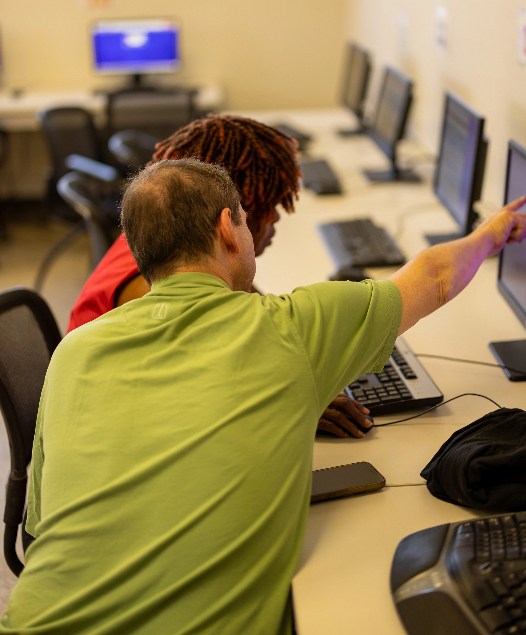a man helps a student use a computer