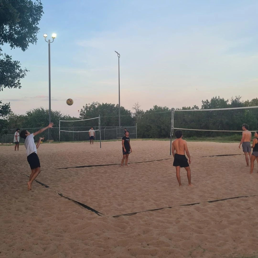 Players playing sand volleyball at Dick Nichols District Park as the sun sets