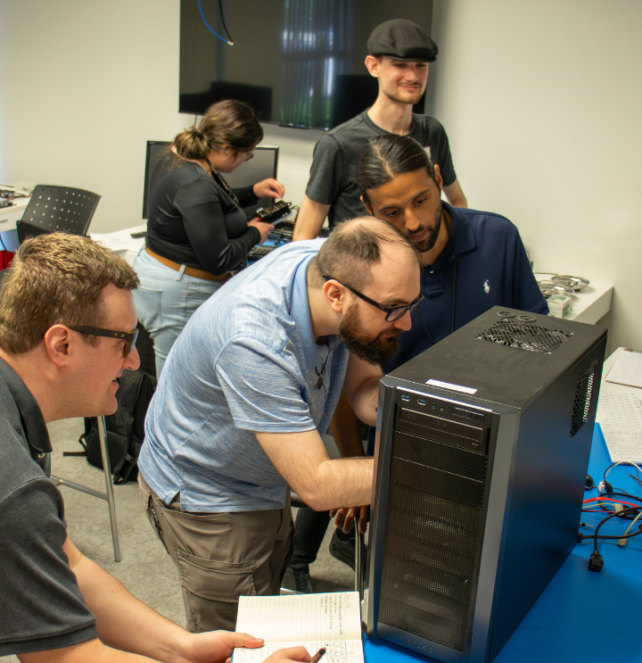 a group of 4 students examine the motherboard of a computer.