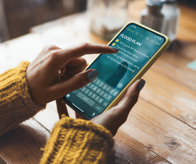 A person holding a phone and going through a flood preparedness checklist.