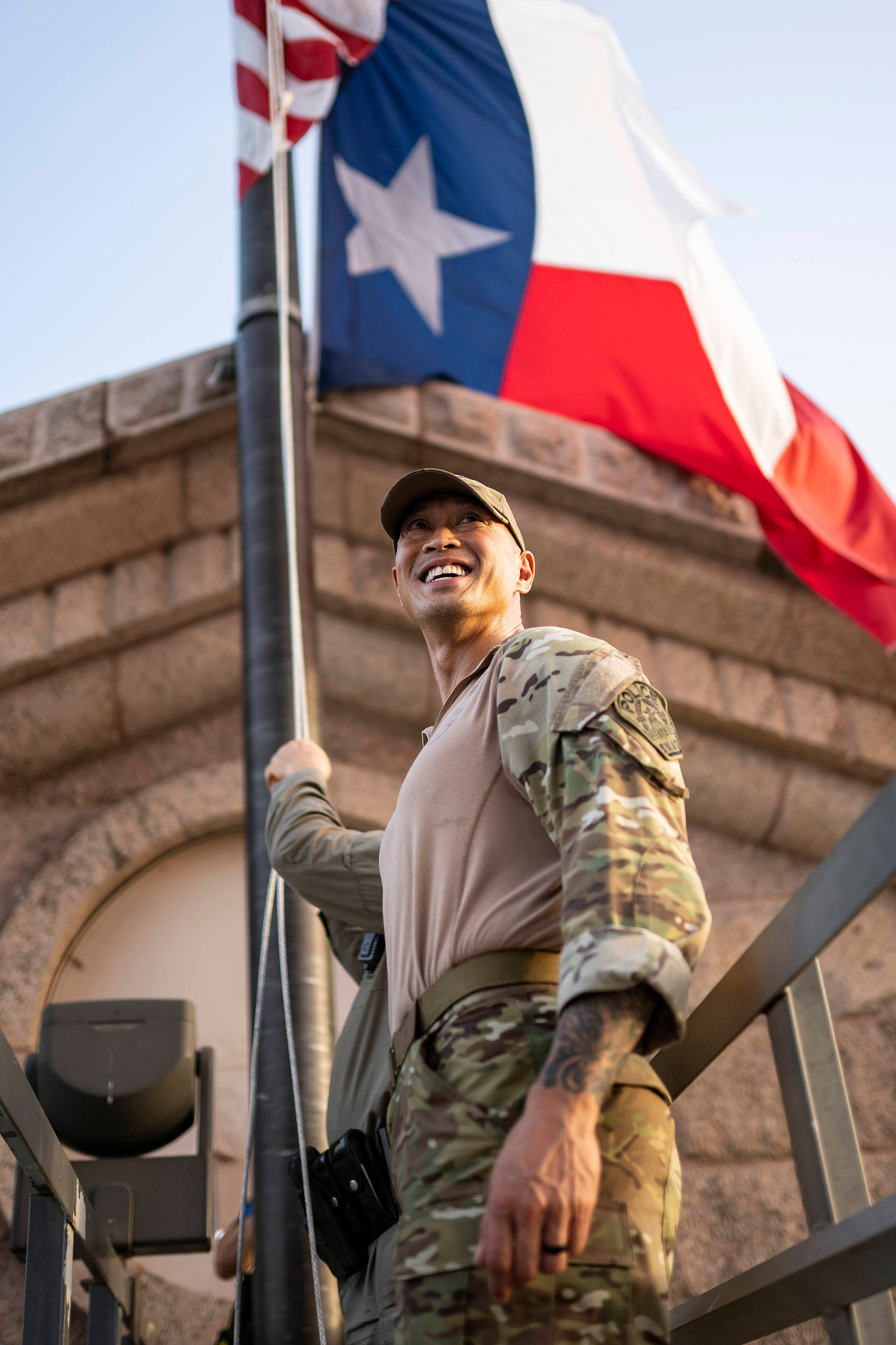 An Austin Police Officer stands in front of American and Texas State flags.