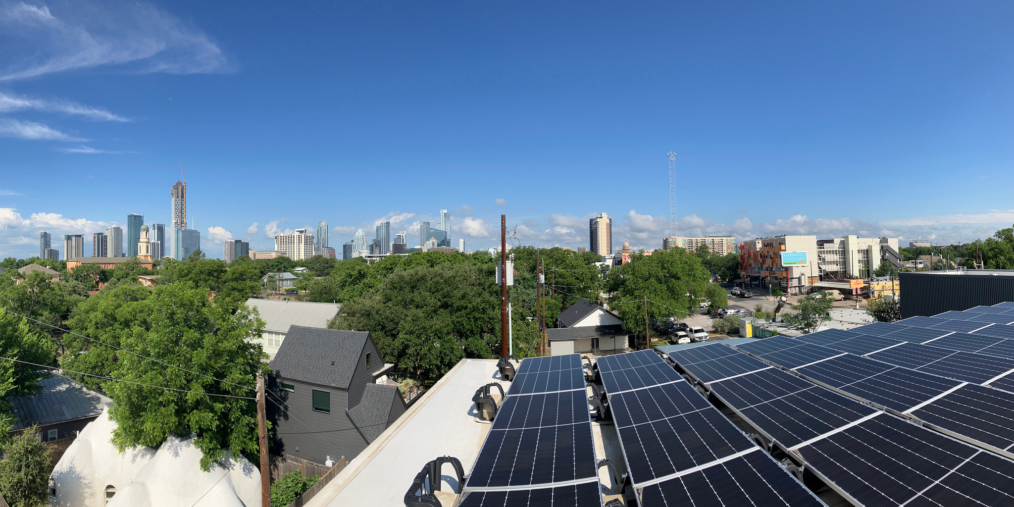 Rooftop solar array taken from the roof with Austin skyline in the background with a clear blue sky and a few clouds.