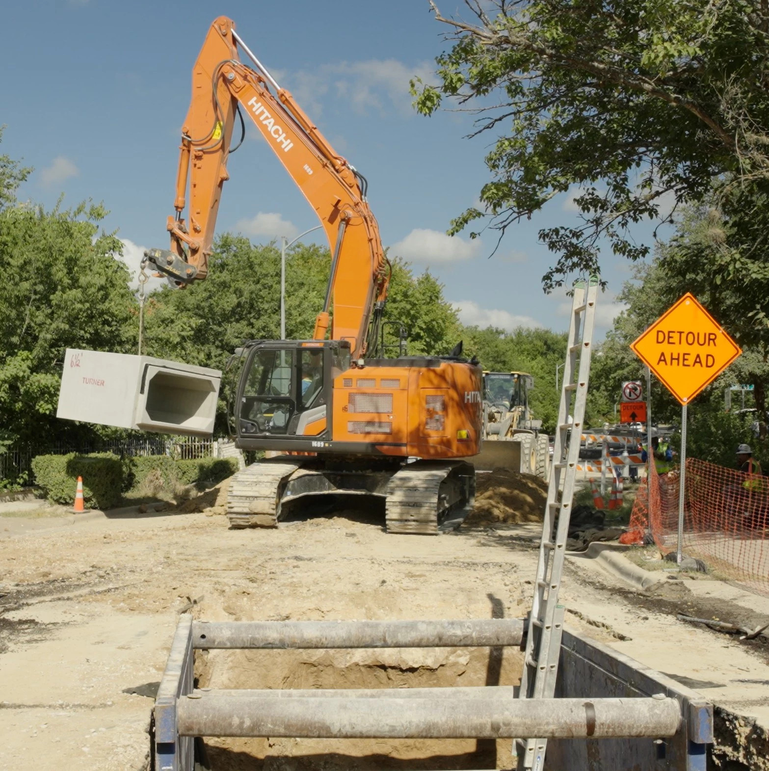 Equipment lifting box culvert into open trench in the road