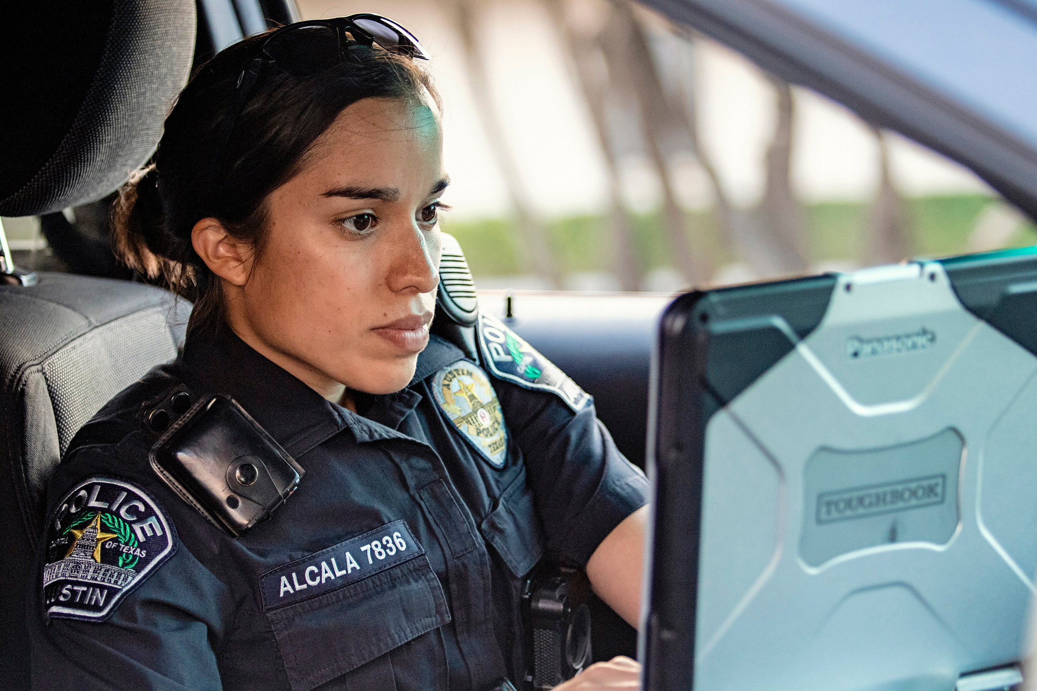 An Austin Police Officer uses a laptop inside of their patrol vehicle.