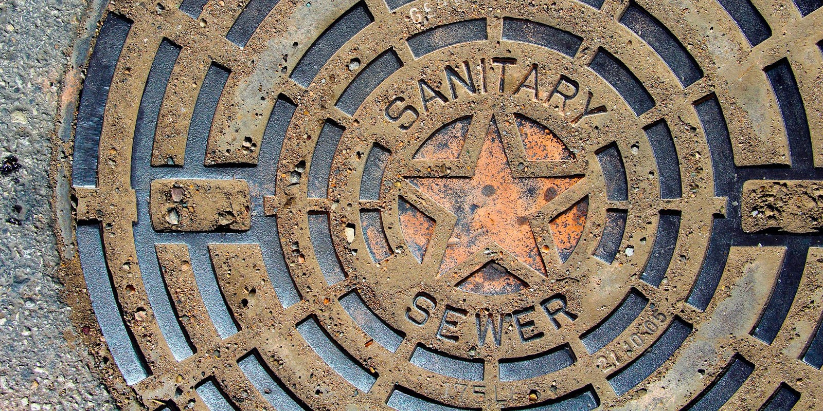 A close-up view of an Austin Water sanitary sewer manhole cover