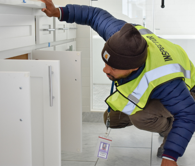 Inspector wearing a vest looking in a cabinet