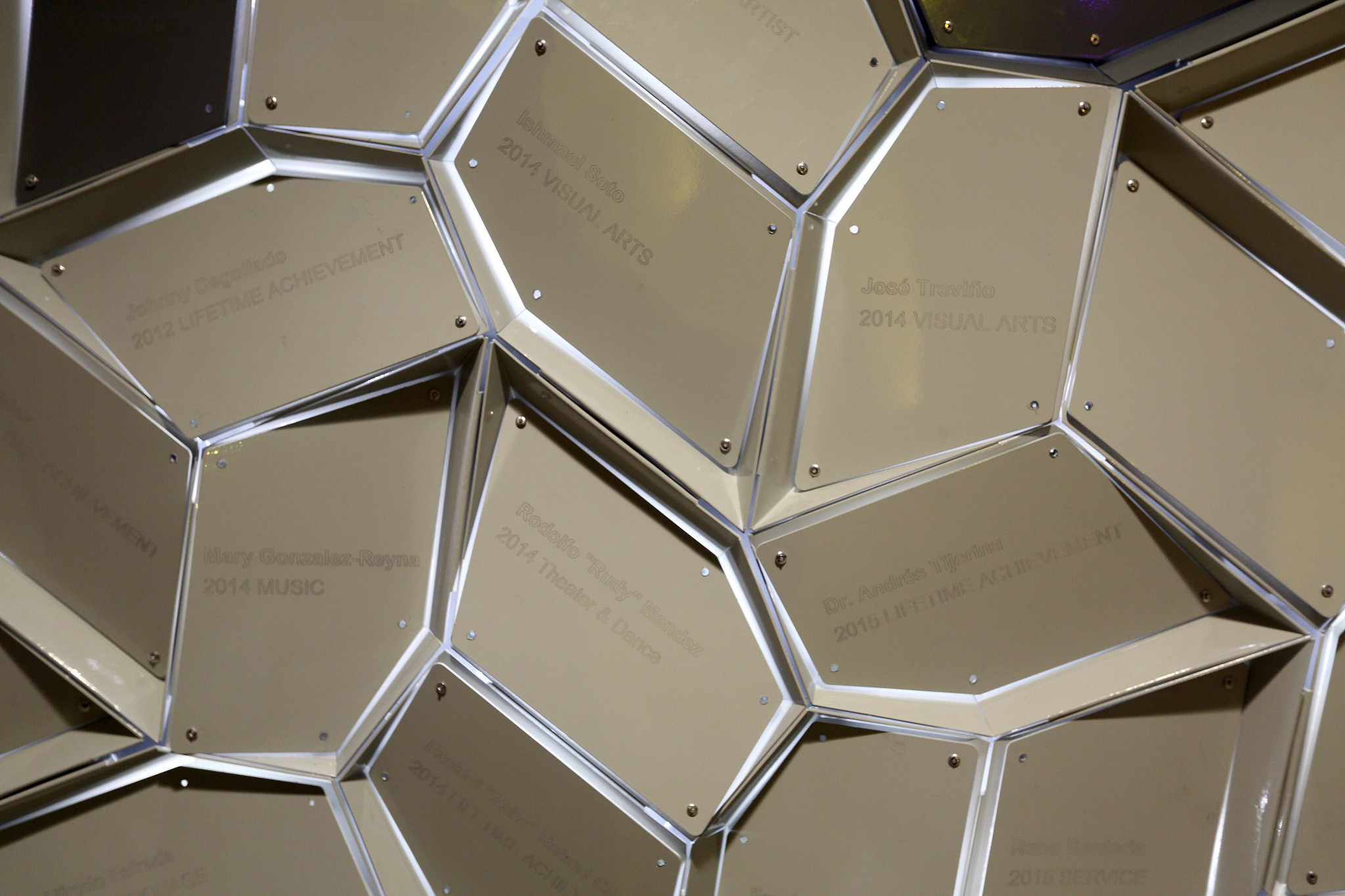 Close up of an outdoor sculpture with names engraved on the face of the petal-shaped ligaments