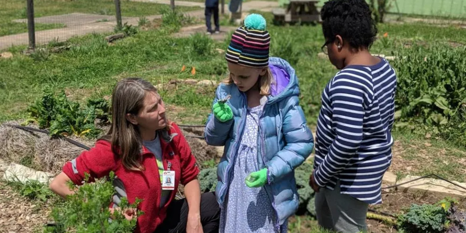 An adult and two children in a garden.