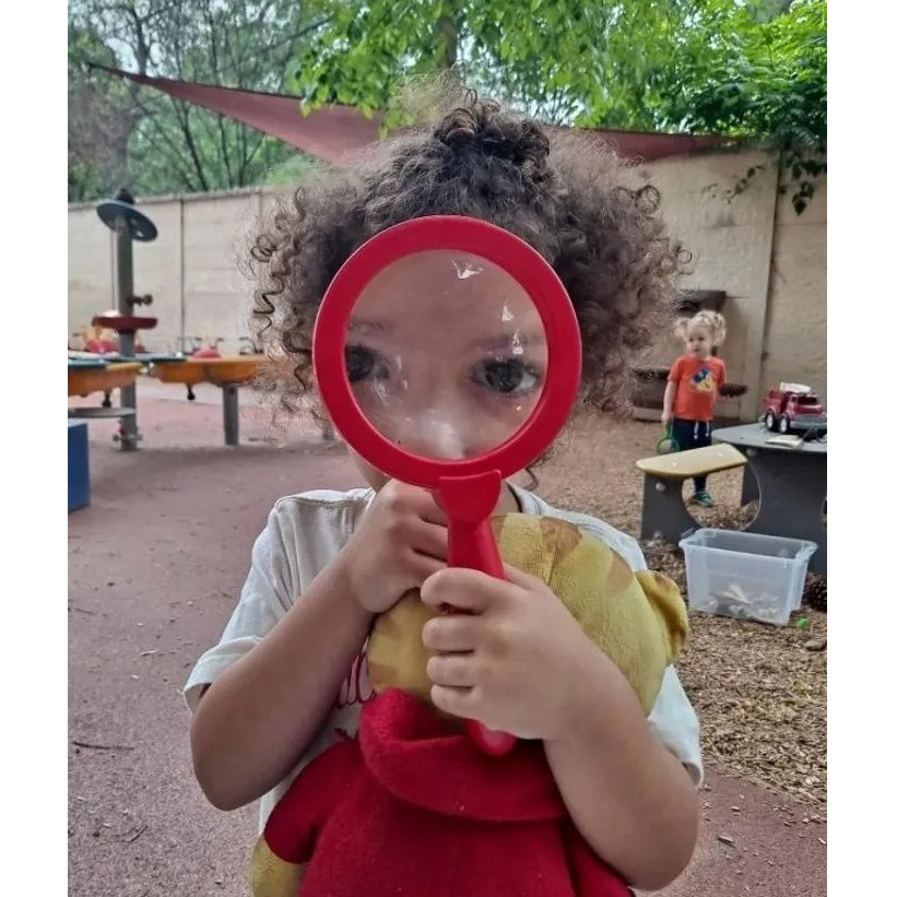 A child holds up a magnifying glass to the camera