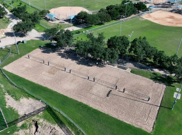 Overhead view of sand volleyball courts in spring with softball fields and trees around the courts