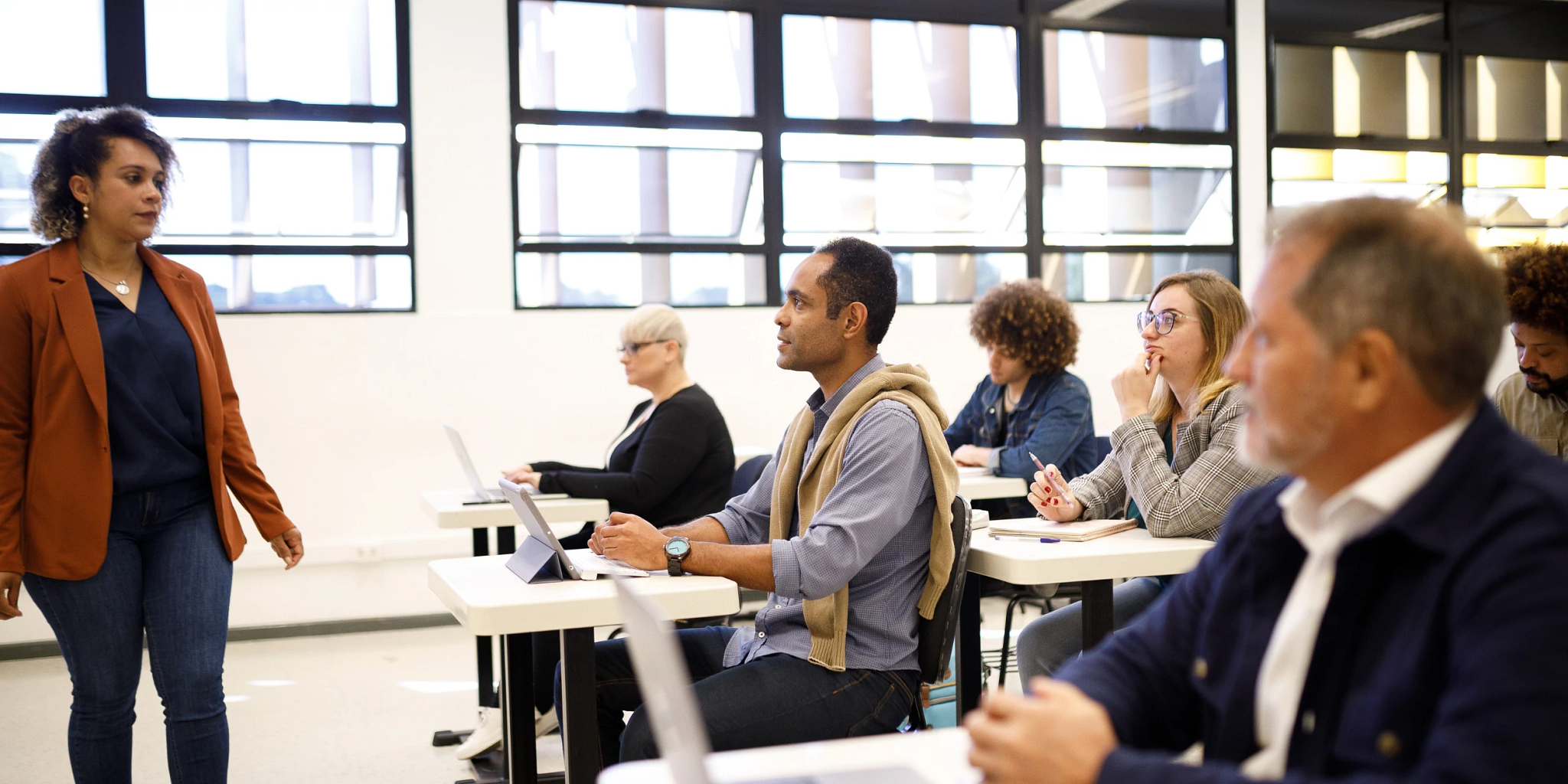 photograph of a woman standing at the head of a classroom, instructing adults