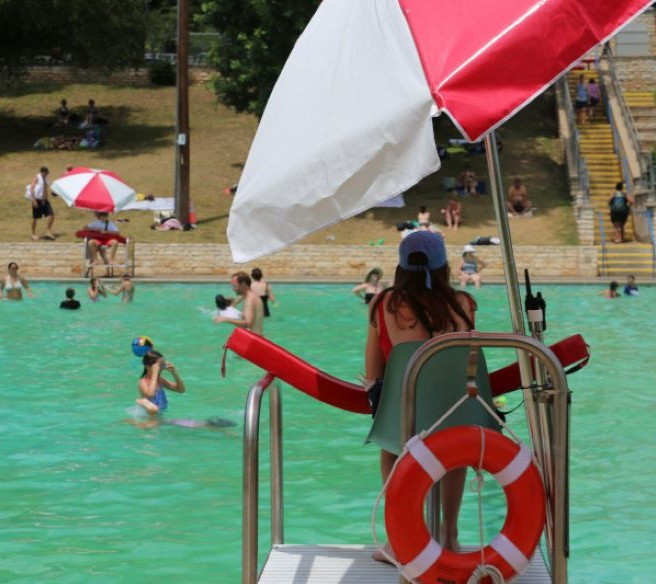 A lifeguard watches over swimmers at Deep Eddy Pool