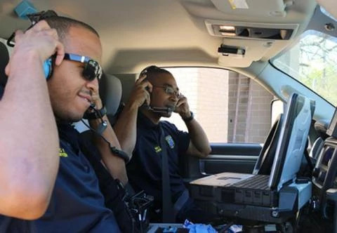 Two smiling EMTs in an ambulance wearing headphones.