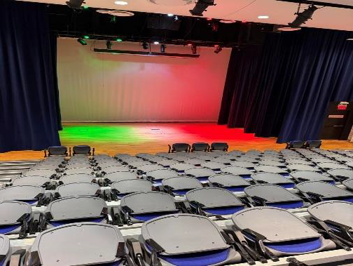 Emma S. Barrientos Mexican American Cultural Center empty auditorium with retractable seats, wood flooring, and a large stage area