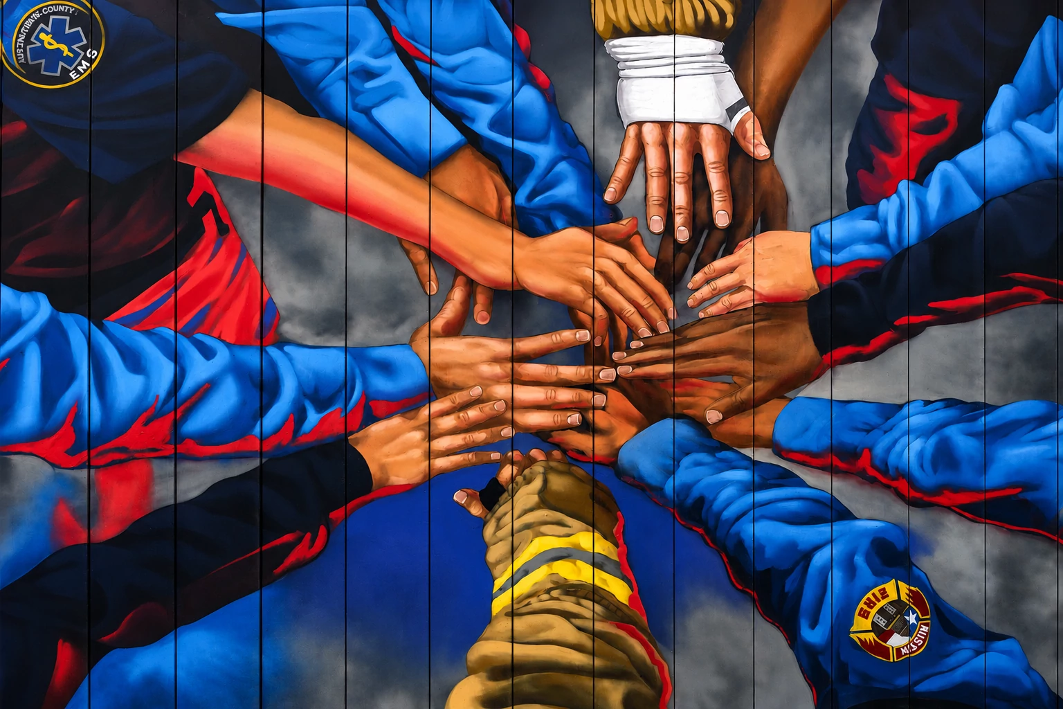 Painted mural on EMS station. Shows hands in a collective.